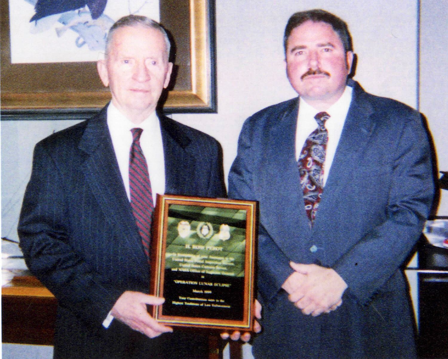 Ross Perot (left) is presented with a plaque by special agent Joseph Gutheinz (right)...