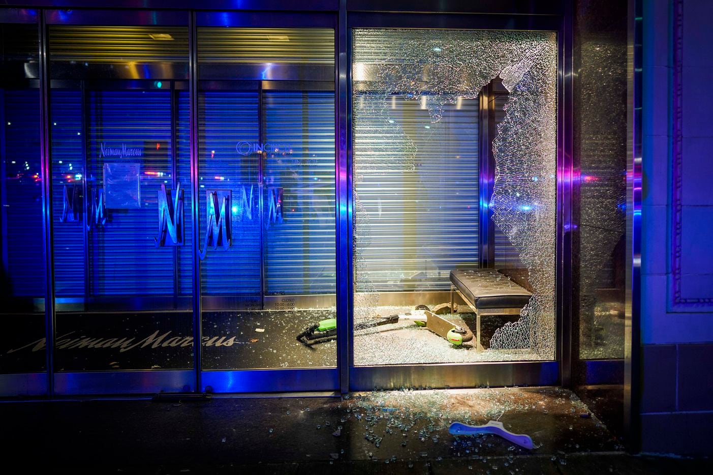 A rental scooter rest amidst broken glass after windows were smashed at the Nieman Marcus...