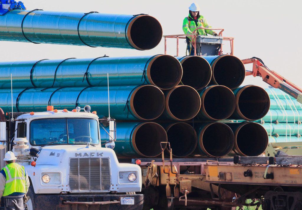 FILE - In this May 9, 2015, file photo, workers unload pipes for the proposed Dakota Access...