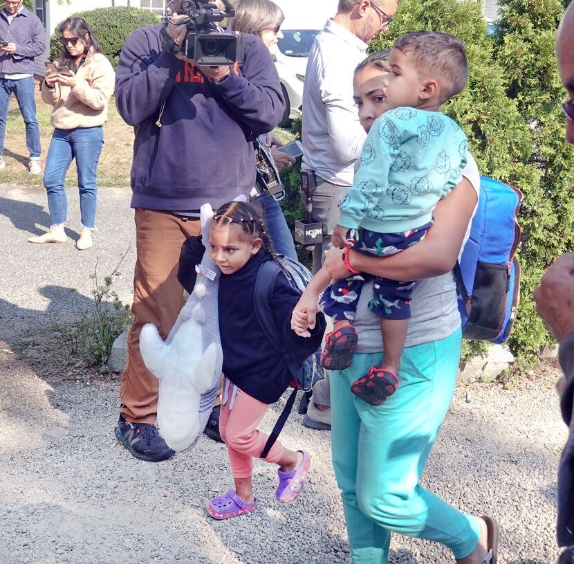 An immigrant family makes their way to the bus transporting from St. Andrews in Edgartown,...