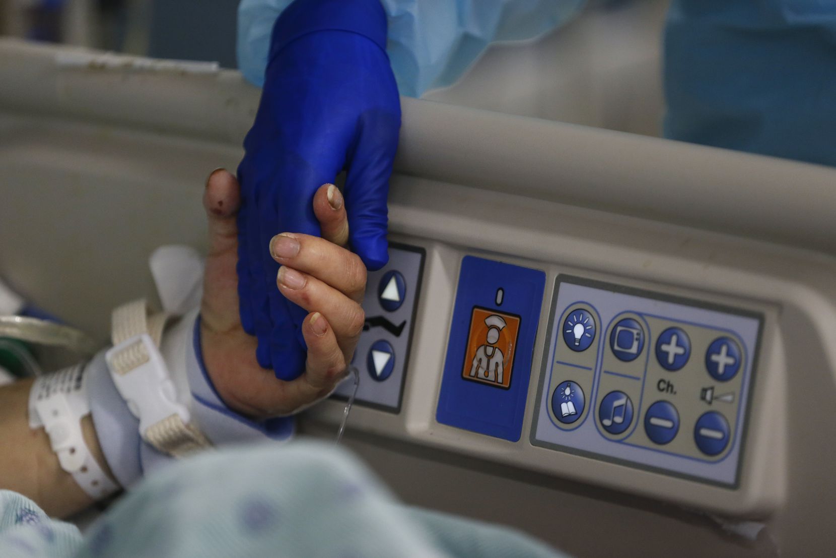 A 73-year-old intubated intensive care COVID-19 patient reached for the hand of a nurse as...
