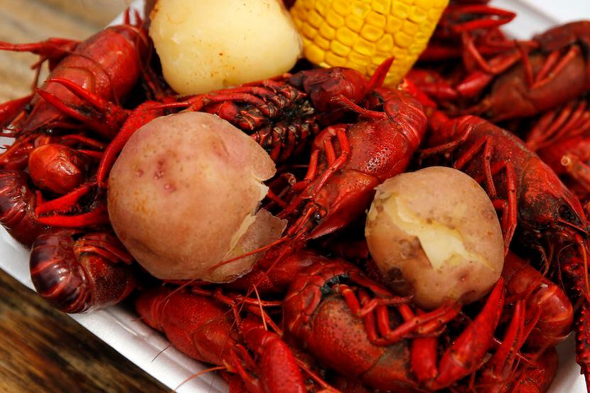 A clamshell plate of boiled crawfish, potatoes and corn sits on a table during the Frisco...