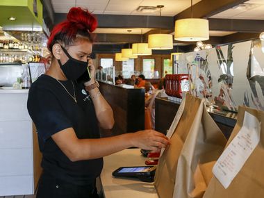 Liberty Burger employee Nicole Romero checks a takeout order while answering the phone at Liberty Burger in Dallas.