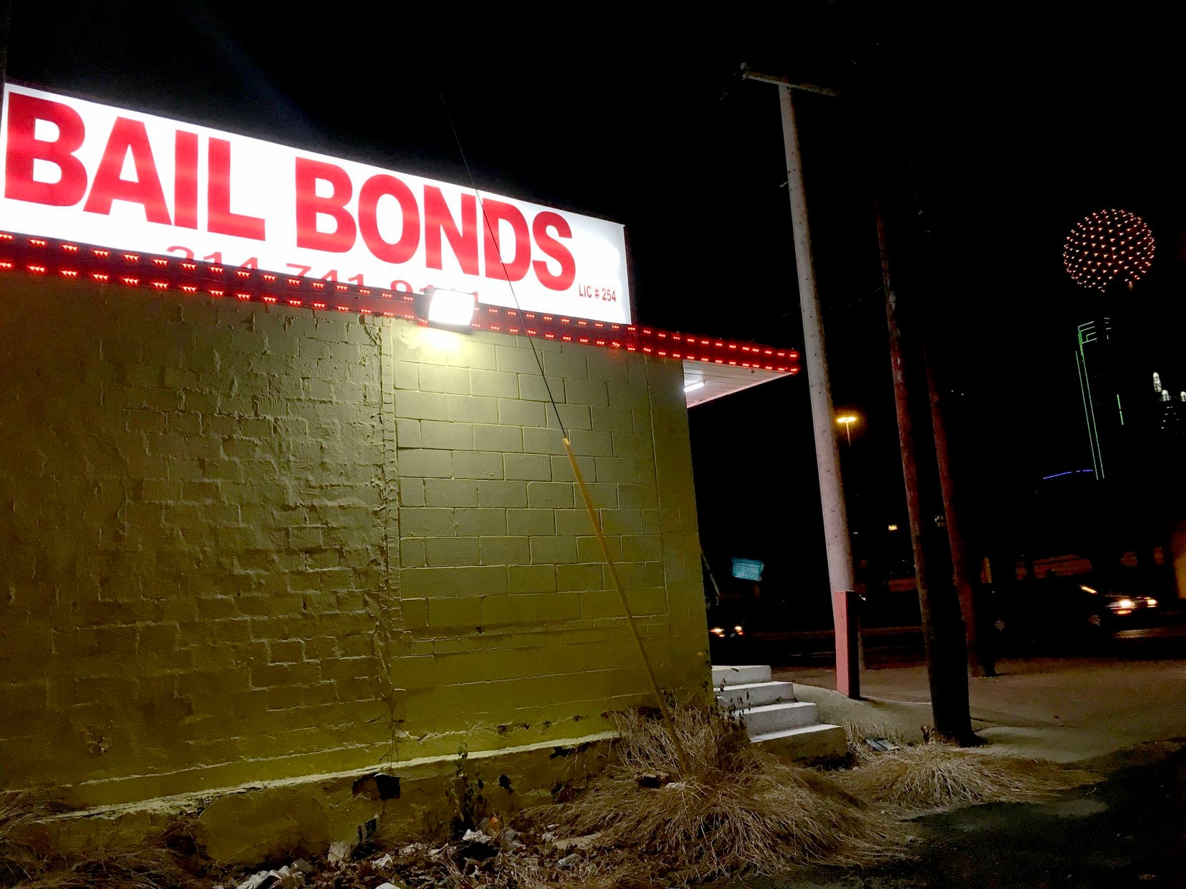 Lights from a bail bond business glow along Riverfront Blvd. in Dallas, on Sunday night,...