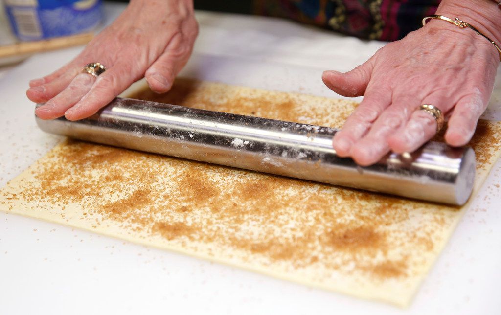 After getting brown sugar sprinkled onto puff pastry, use a roller to press in the sugar to...