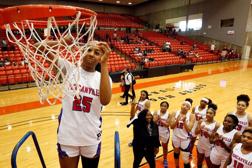 Duncanville's Deja Kelly (25) cuts a piece of the net after she and her teammates defeated...