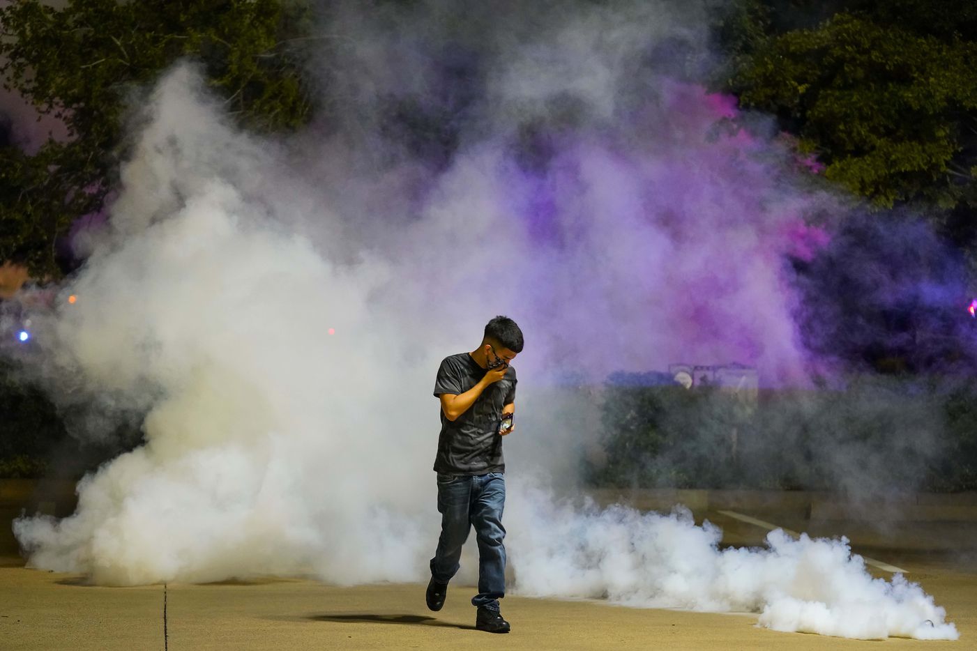 A protester runs away after a canister of teargas landed at his feat as Dallas police...