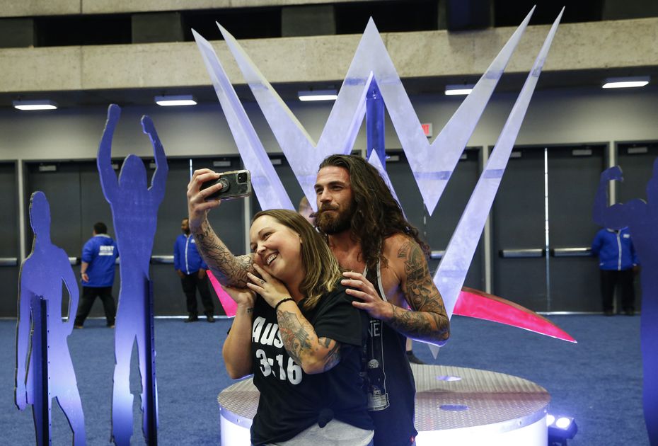 Shane Thomas, back, takes a selfie with Jessica in front of a WWE symbol during an...