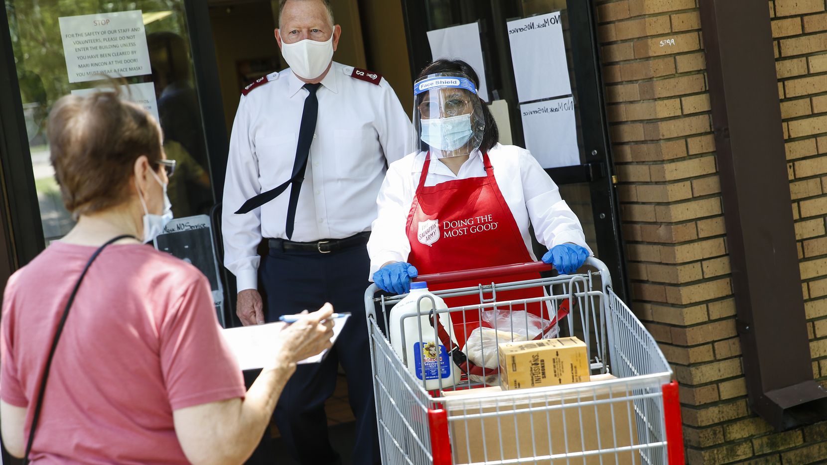 Salvation Army Major Todd Hawks, back, assists employee Maria Rincon, center, with a food...