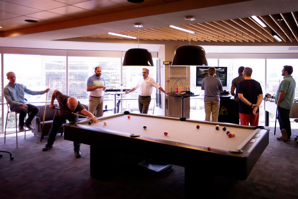 Employees play billiards and video games during a party celebrating employee birthdays at...