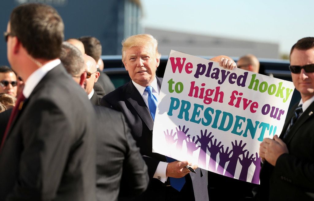 President Donald Trump holds up a supporter's sign for the media while arriving at Love...
