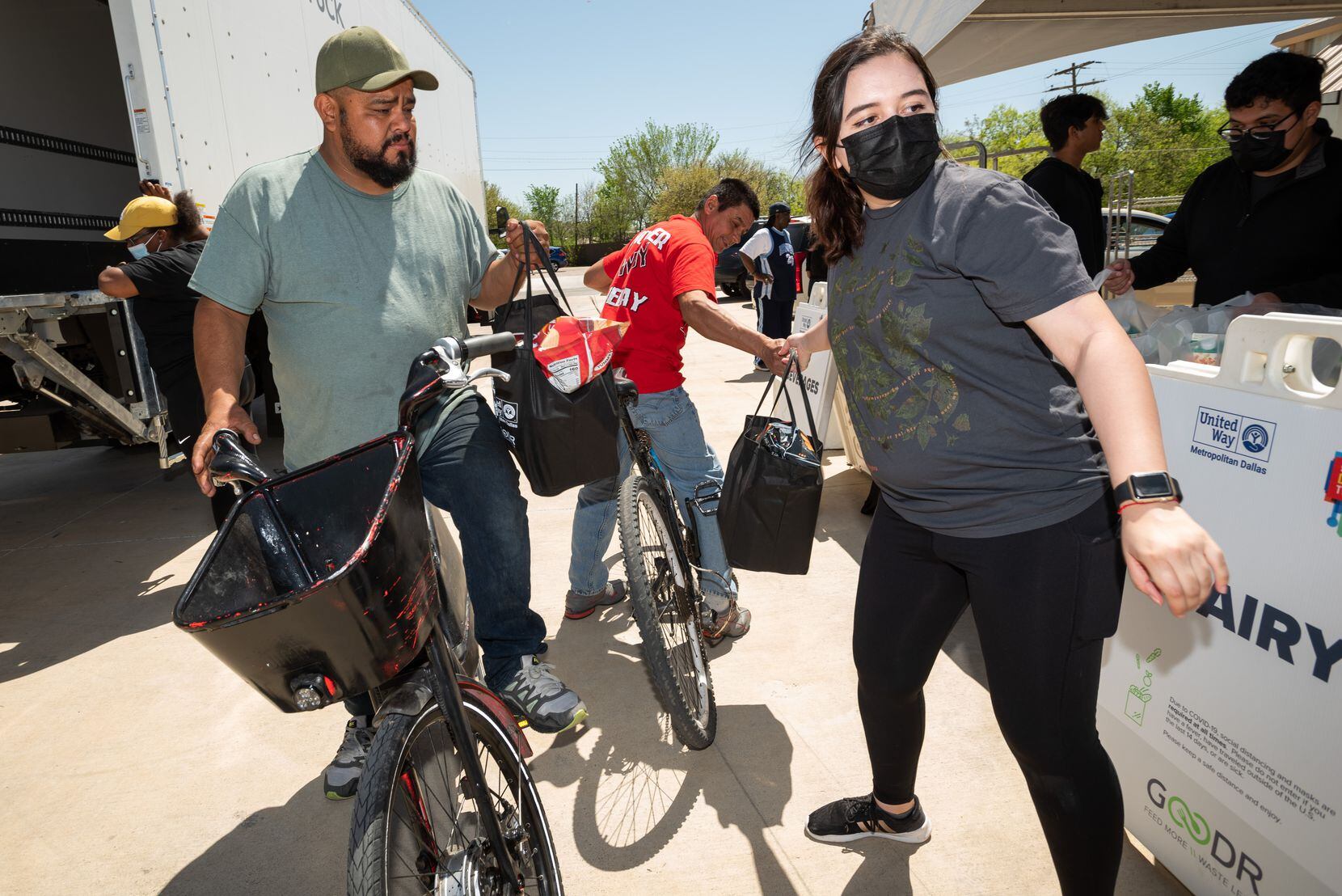 Rocky Munoz (left) and friend Roberto Rodriguez receive bags of free groceries from Goodr...