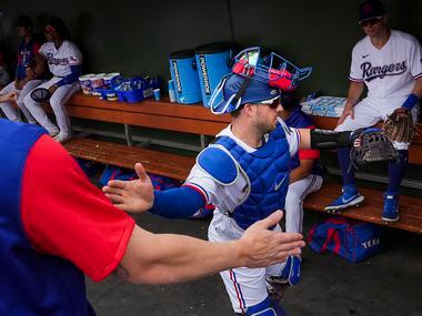 Texas Rangers catcher Mitch Garver slaps hands with teammates catcher Jonah Heim (left) and...