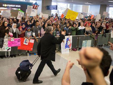 A passenger gives a thumbs up to protestors in the international arrivals hall at DFW...