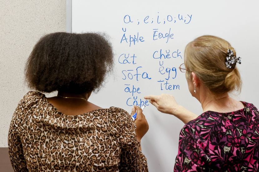Adult education instructor Cynthia White (right) works on English vowel sounds with a...