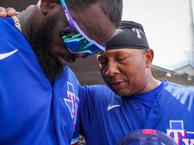 Texas Rangers outfielder Adolis García (left) prays with third base coach Tony Beasley in...