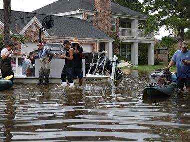 People use boats to help bring items out of homes in the Houston area where torrential rains...