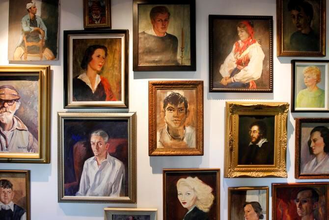 
A collection of painted portraits, displayed gallery style, lines both sides of the hallway. 
