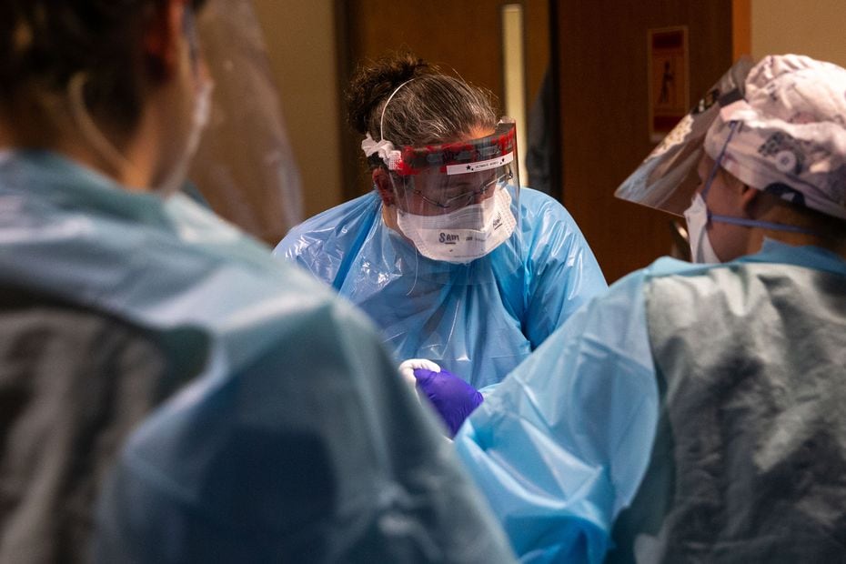 Samantha Rowley (center), Parkland's senior vice president of nursing for surgical services, helps change the bedding of a COVID-19 patient who was just intubated in the hospital's Tactical Care Unit.