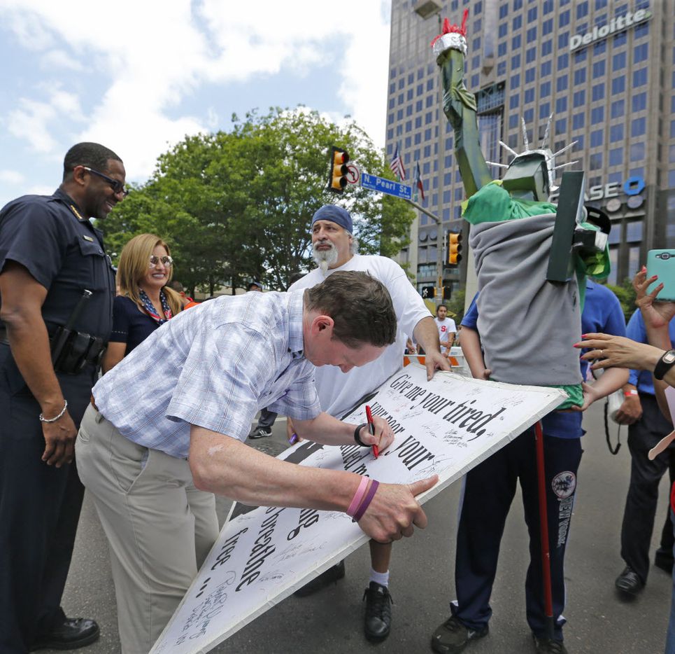 Dallas County Judge Clay Jenkins signs a poster during the Mega March, which started at the...