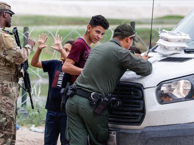 A migrant boy holds his hands up to indicate that he is 10-years-old after being asked his...