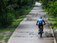 A person rides a bike at the White Rock Lake trail as expected heavy rainfall starts to fall...