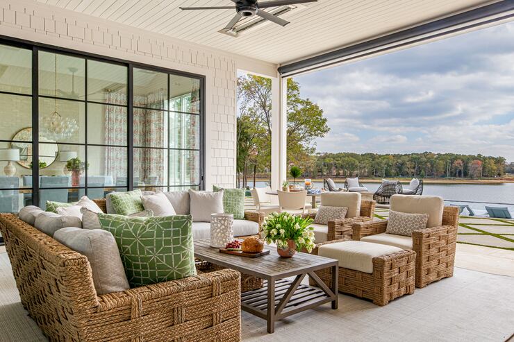 Covered patio at a lakefront home, with an outdoor sofa and coffee table, white flowers, and...