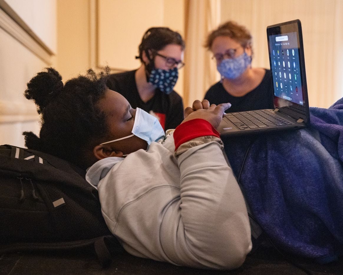(From left) Madison Lewis, 10, uses a laptop as Thomas Stuteville and Karen Arnold chat as they seek refuge at the warming center located at Ruthe Jackson Center in Grand Prairie on Tuesday, Feb. 16, 2021. The family lost power at 12:16pm on Monday. (Juan Figueroa/ The Dallas Morning News)