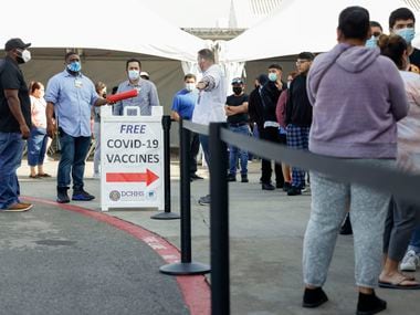 People wait in line at a COVID-19 vaccination clinic at the Walmart on North Cockrell Hill in Dallas, Wednesday, Dec. 29, 2021.