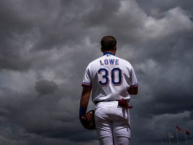 Texas Rangers infielder Nathaniel Lowe stands for the national anthem as clouds from a...