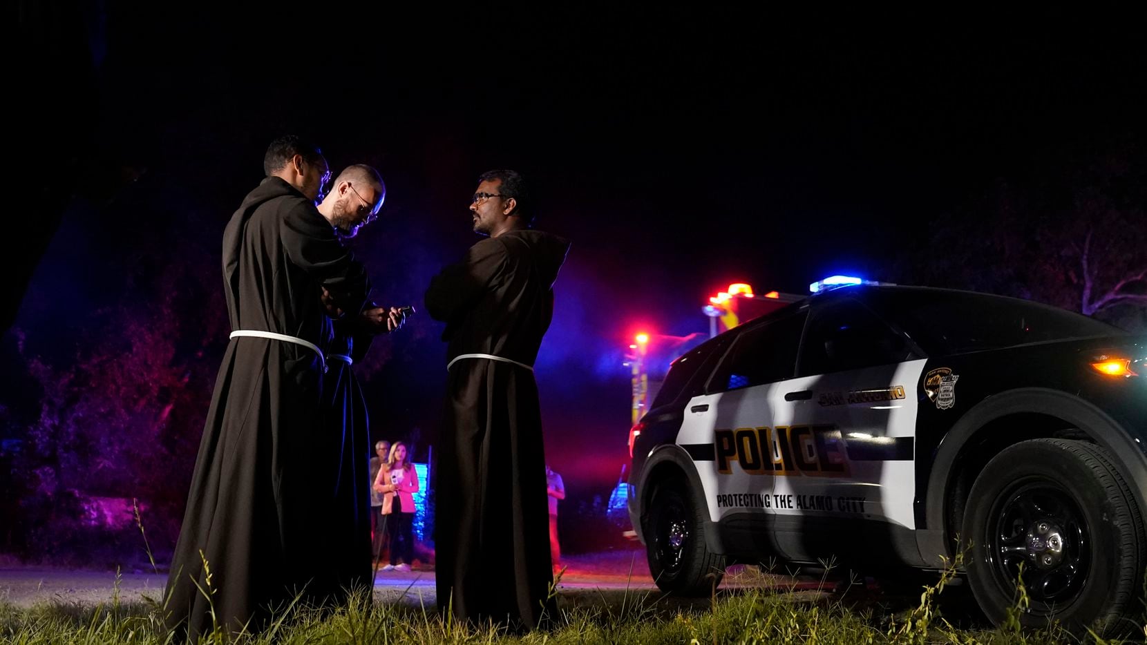 Priests gather near the scene where officials say dozens of people have been found dead and...