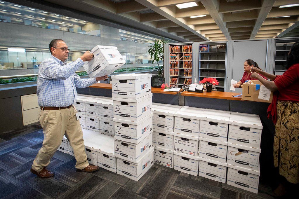 Assistant city secretary Jesus Salazar (left) stacks and counts boxes of petitions after a...