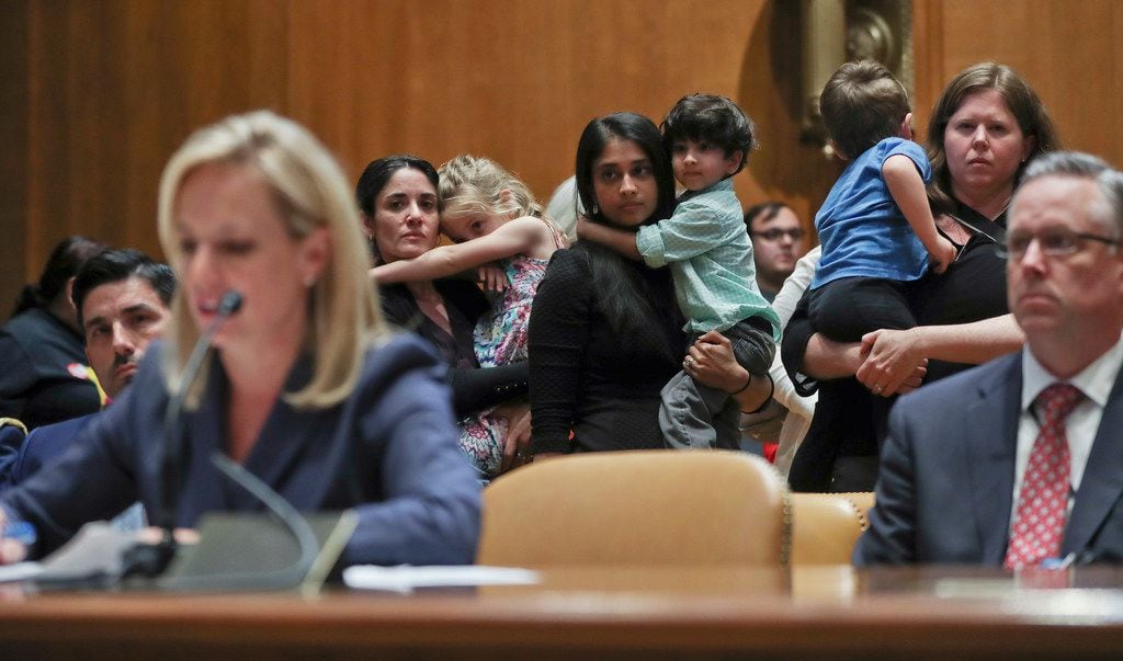 Women carrying children in their arms stand up to protest the opening remarks of Homeland...