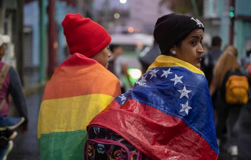 ARCHIVO - Un migrante venezolano lleva su bandera nacional dentro de un grupo de migrantes...