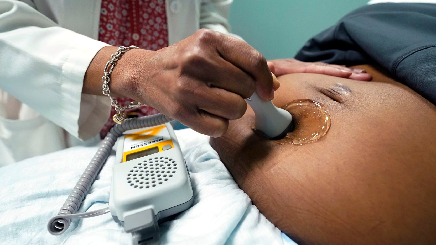 FILE - A doctor uses a hand-held Doppler probe on a pregnant woman to measure the heartbeat...