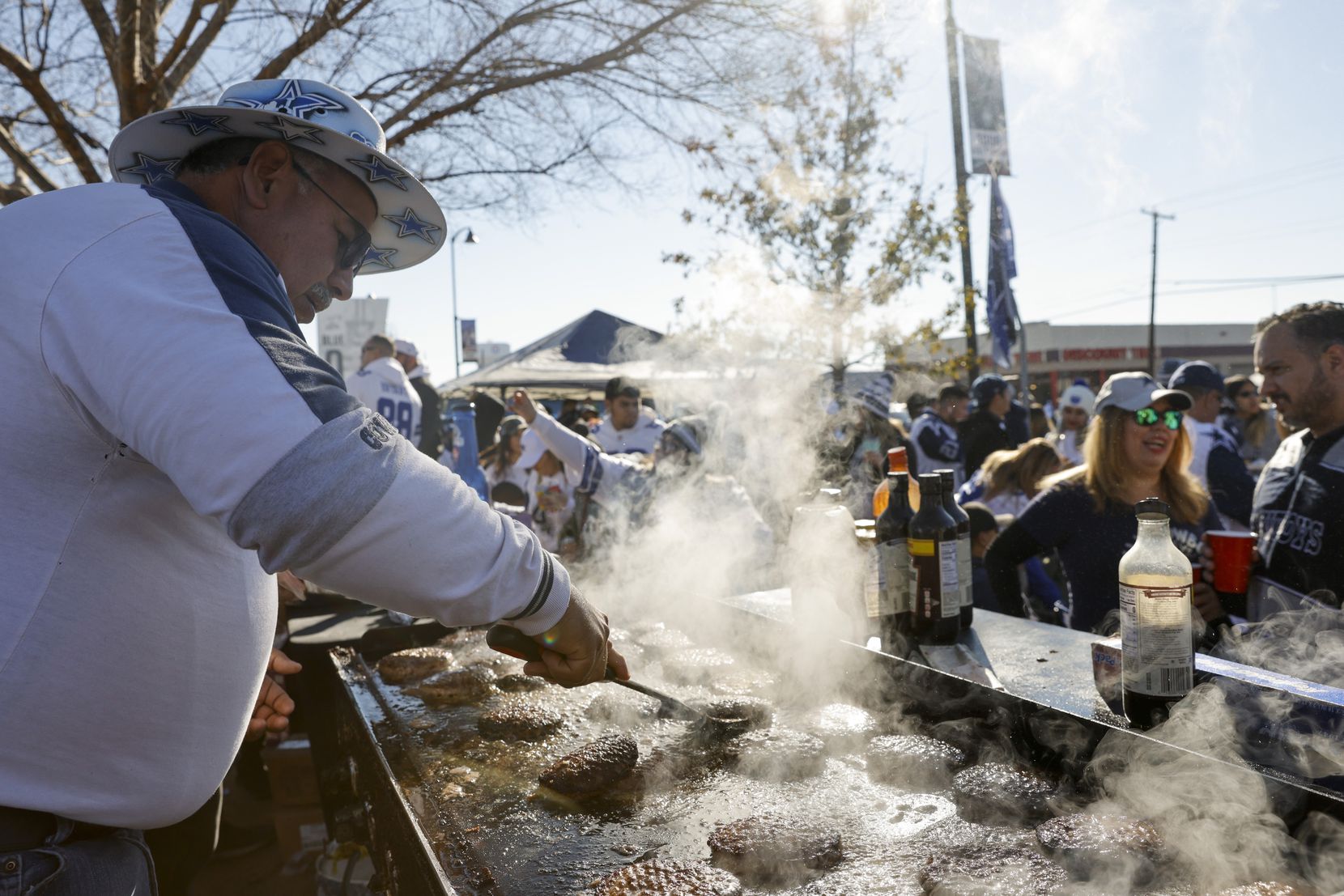 Gilbert Delgado grills hamburgers at a tailgate party before an NFL wild-card playoff game...