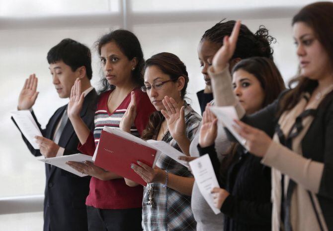 Inmigrantes toman su juramento como nuevos ciudadanos en una ceremonia de naturalización...