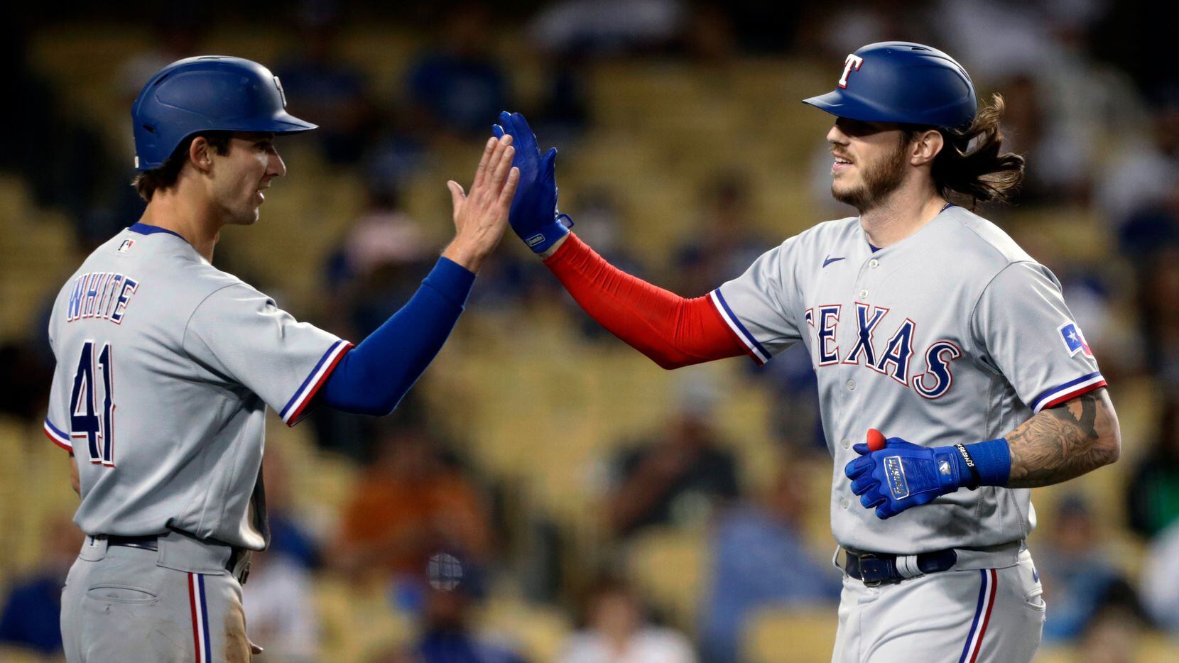 Texas Rangers' Jonah Heim, right, gets congratulations from Eli White after hitting a...
