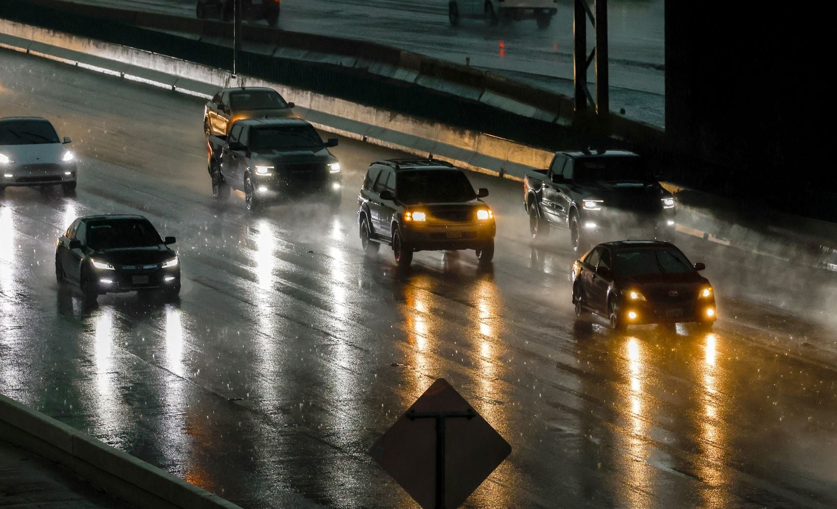 Drivers move along Interstate 35E under the darkness of rain and storm clouds on Thursday,...