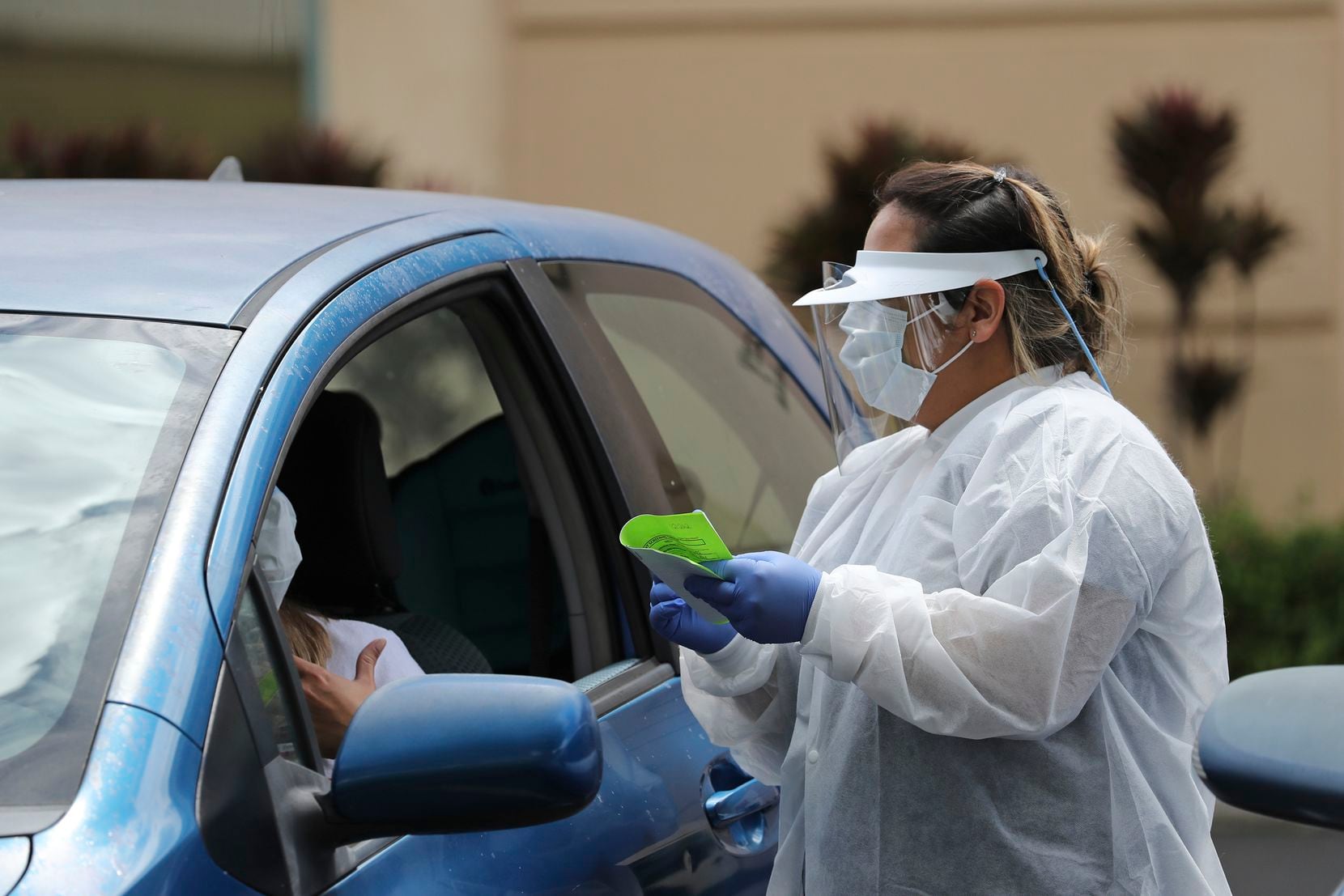 A medical worker at a facility in Pearl City, Hawaii, fully equipped with eye and body protection to test patients in their vehicles. (AP Photo/Marco Garcia)