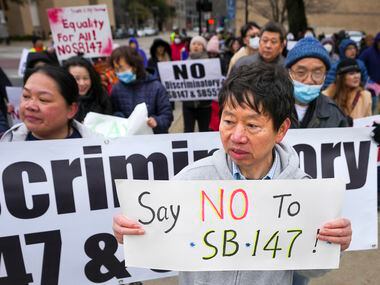 Hank Huang holds a sign reading “Say No To SB-147” as demonstrators march in opposition to...