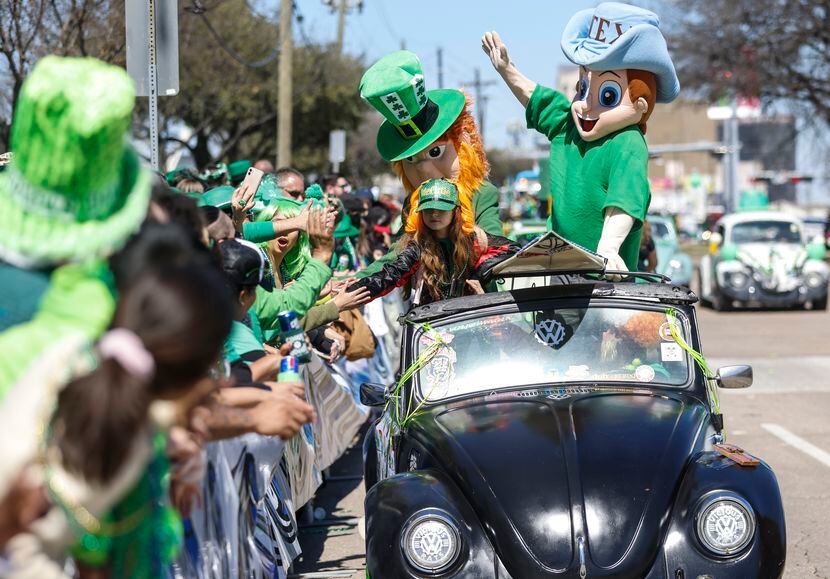 People high-five a girl and a leprechaun in a Volkswagen Beetle during Dallas’ annual St....