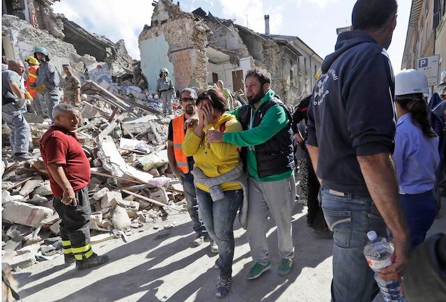 Una mujer es consolada mientras camina por las calles destruidas de Amatrice, en el centro...