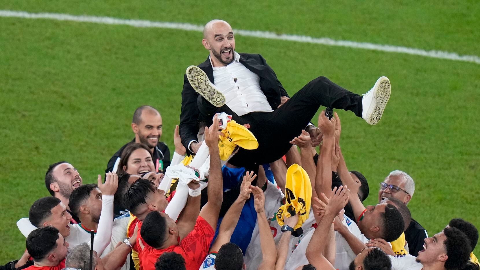 Morocco players celebrate by tossing the head coach Walid Regragui into the air at the end...