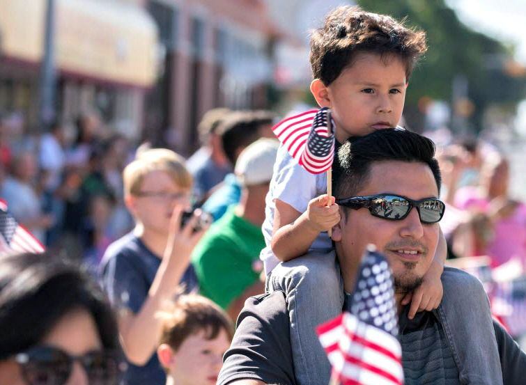Parade spectators wave flags along Main St. in Garland.