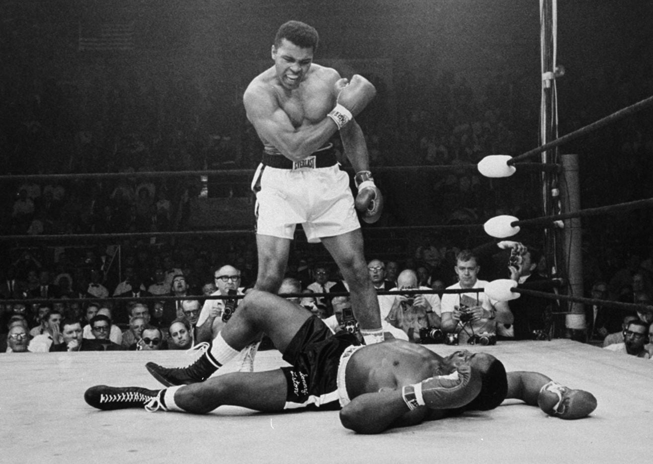 Heavyweight champion Muhammad Ali stands over fallen challenger Sonny Liston, shouting and...
