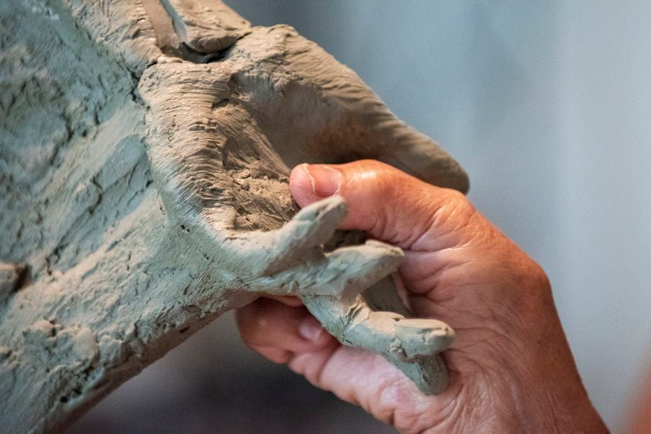Bessie Rodriguez, far right, places her thumb print in the hand of the statue made in the image of her son Santos Rodriguez, as sculptor Seth Vandable helps her with the process at Vandable's studio in Cedar Hill, on Tuesday, July 20, 2021. Additional clay was added and heated so Rodriguez could place her print in the statue. Santos, was a 12 when killed by a Dallas Police officer 48 years ago. 