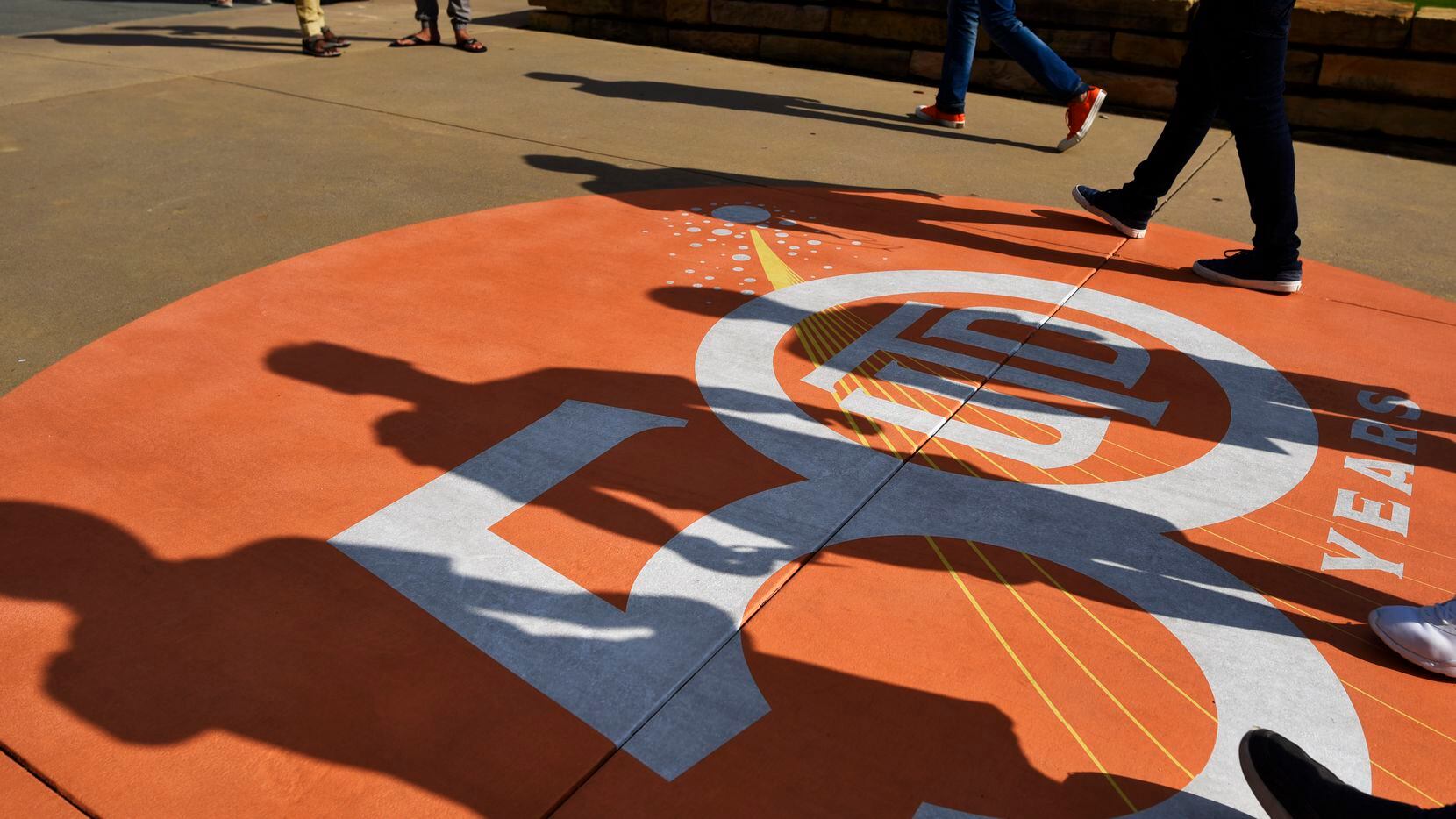 Shadows from freshman walk over a 50th anniversary logo celebrating 50 years of the...
