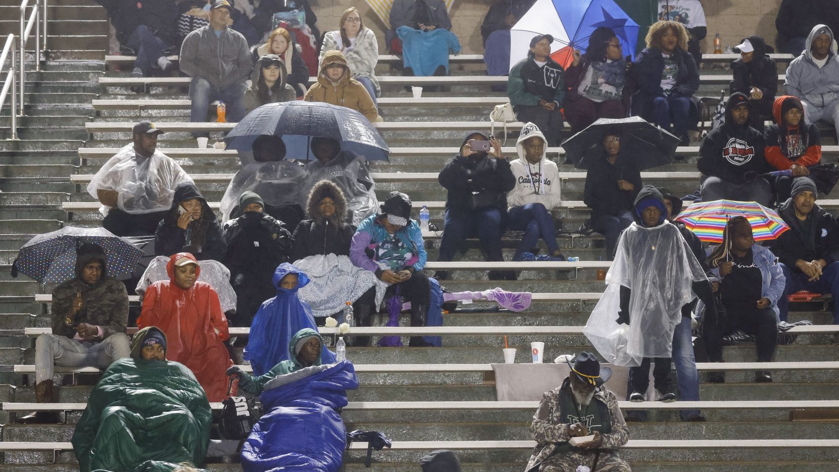 Crowd packed against cold and rain watch a football game between Mansfield Lake Ridge and...