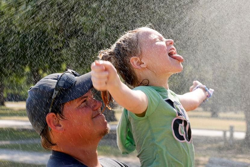Stormie Thornton, de 7 años, se refresca con agua de un aspersor en Trinity Park, en Fort...